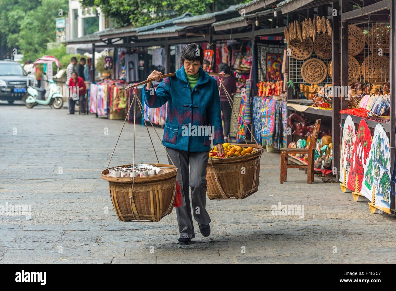 Donna cinese trasporta ceste di produrre e frutta da vendere nel mercato locale di Yangshuo, Cina Foto Stock
