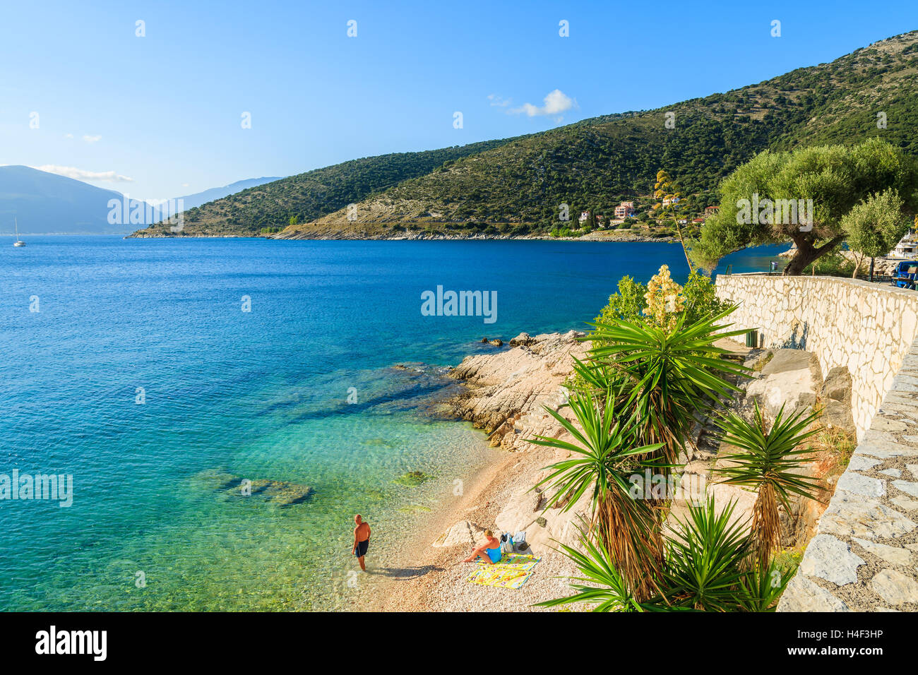 Unidentified paio di persone a rilassarsi sulla spiaggia sulla costa dell'isola di Cefalonia in Agia Efimia, Grecia Foto Stock