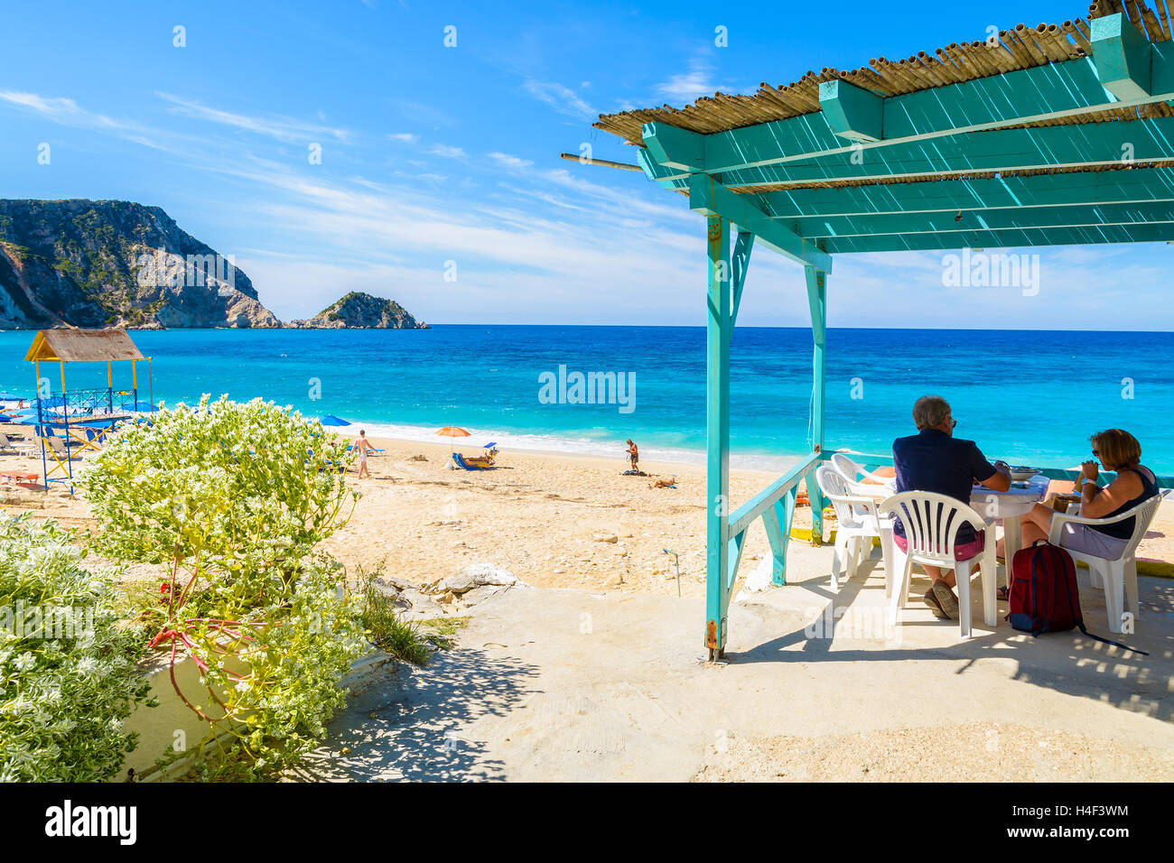 Unidentified paio di turisti sedersi in una tradizionale taverna greca sulla spiaggia di Petani, l'isola di Cefalonia, Grecia Foto Stock