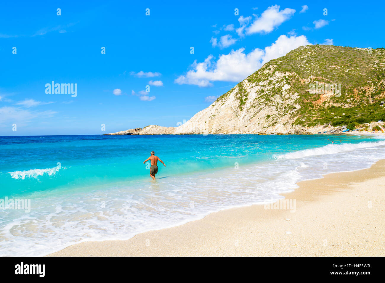 Unidentified uomo a camminare in acqua del mare turchese sulla spiaggia di Petani,l'isola di Cefalonia, Grecia Foto Stock