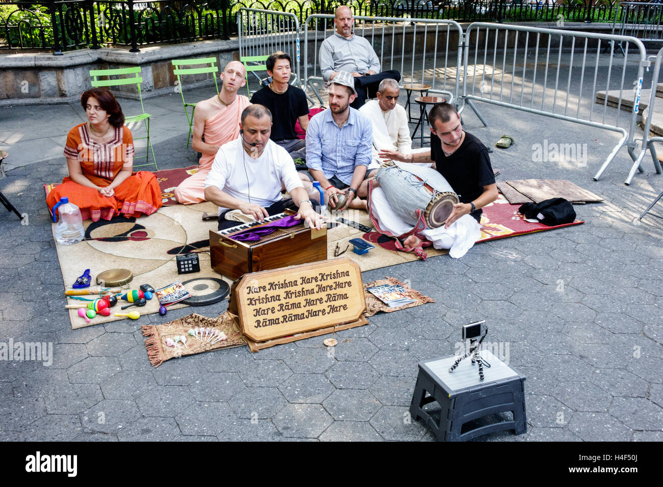 New York City,NY NYC Manhattan,Stuyvesant Square,parco pubblico,Hare Krishna,religione,culto,Asian adult,adults,man men maschio,woman female women,sitting on Foto Stock