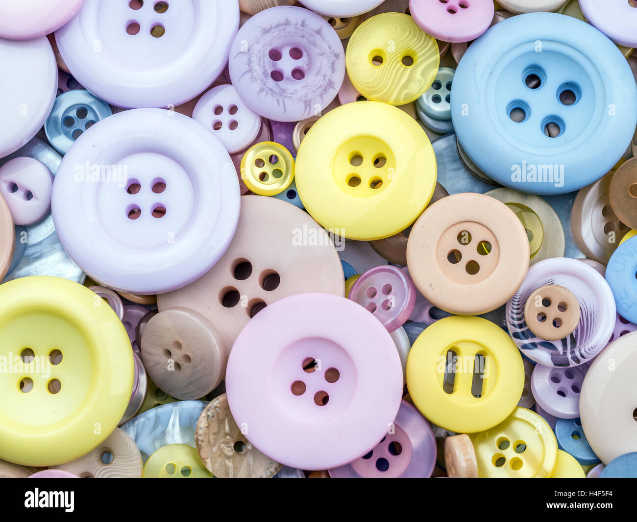 Pila di pulsanti di capi di abbigliamento in diverse taglie e colori shot dal di sopra Foto Stock