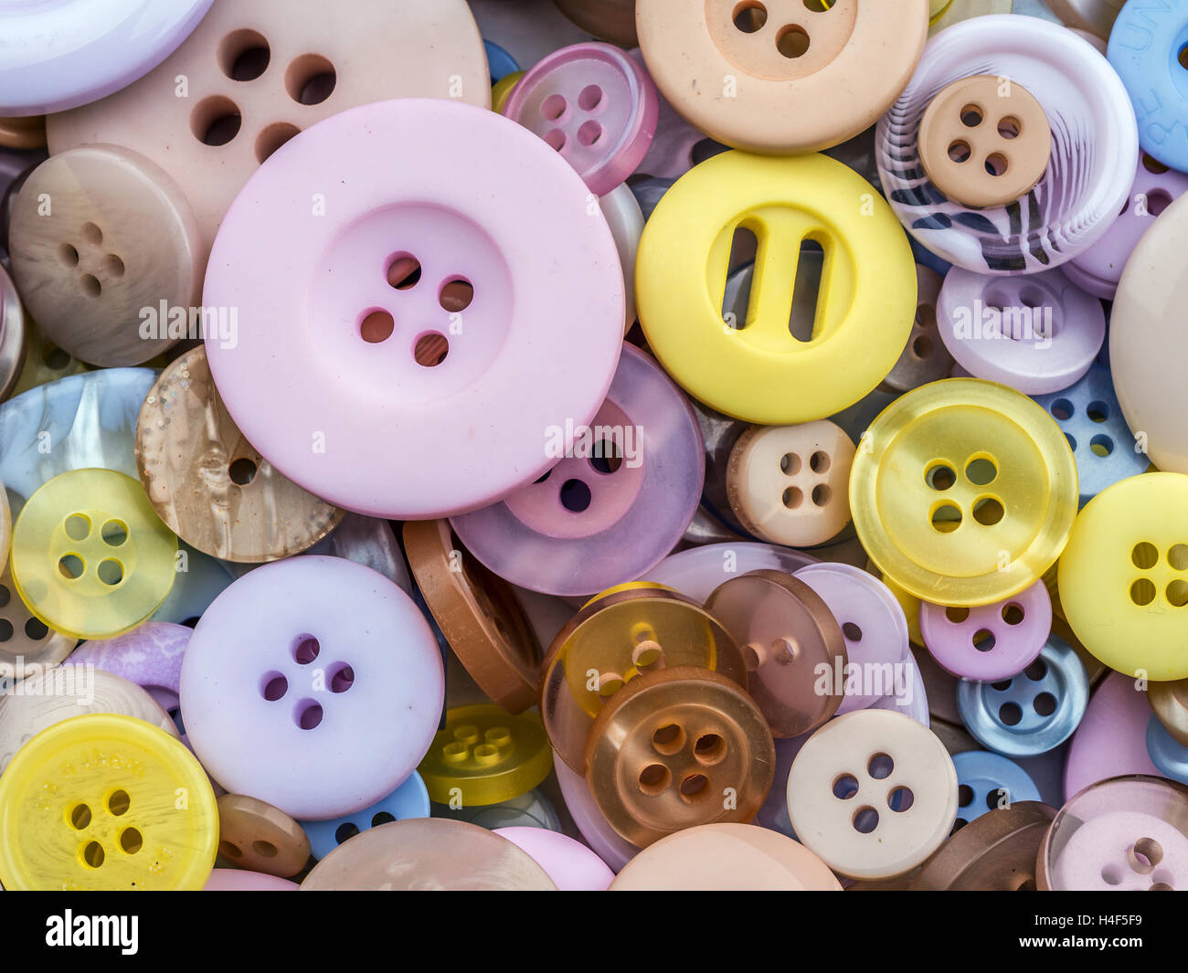 Pila di pulsanti di capi di abbigliamento in diverse taglie e colori shot dal di sopra Foto Stock