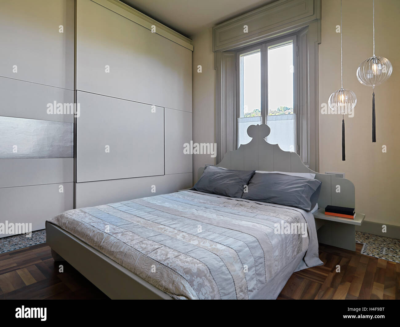 Vista interna di una moderna camera da letto con pavimento in legno e un armadio Foto Stock