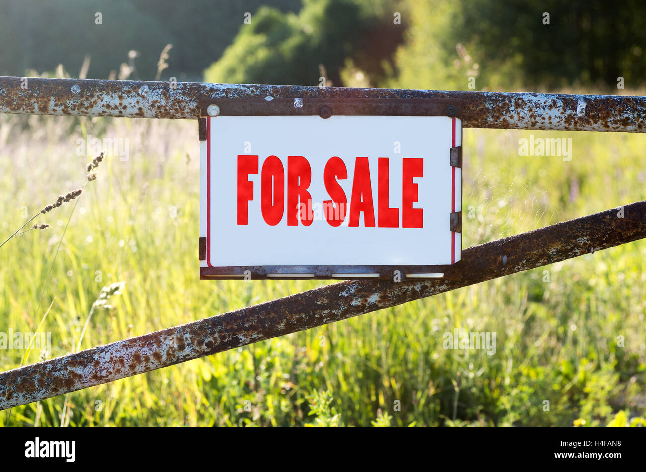 Segno per la vendita su una porta di metallo sulla strada sterrata Foto Stock