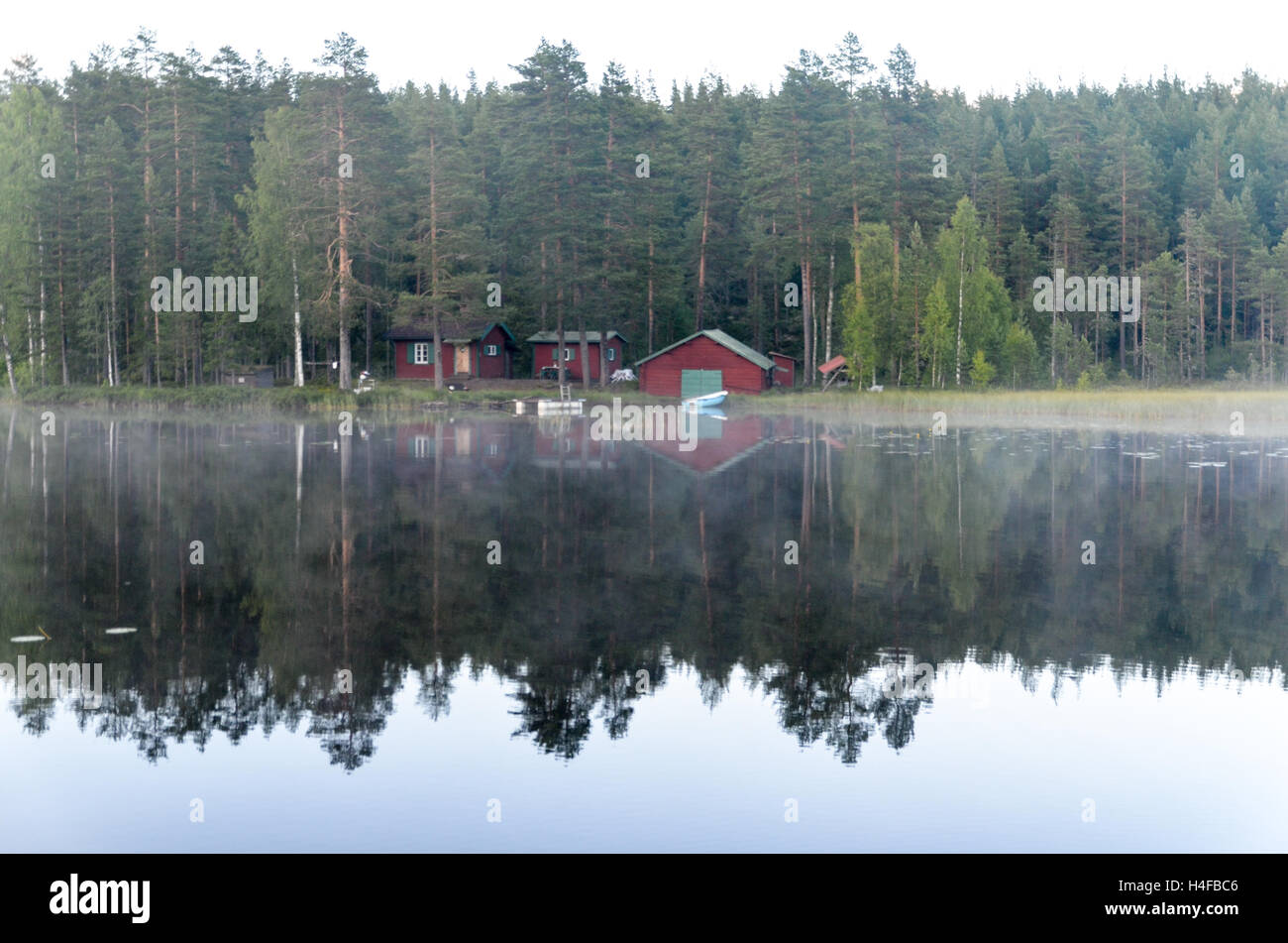Lakehouse riflettendo nel lago in una foresta, Svezia Foto Stock