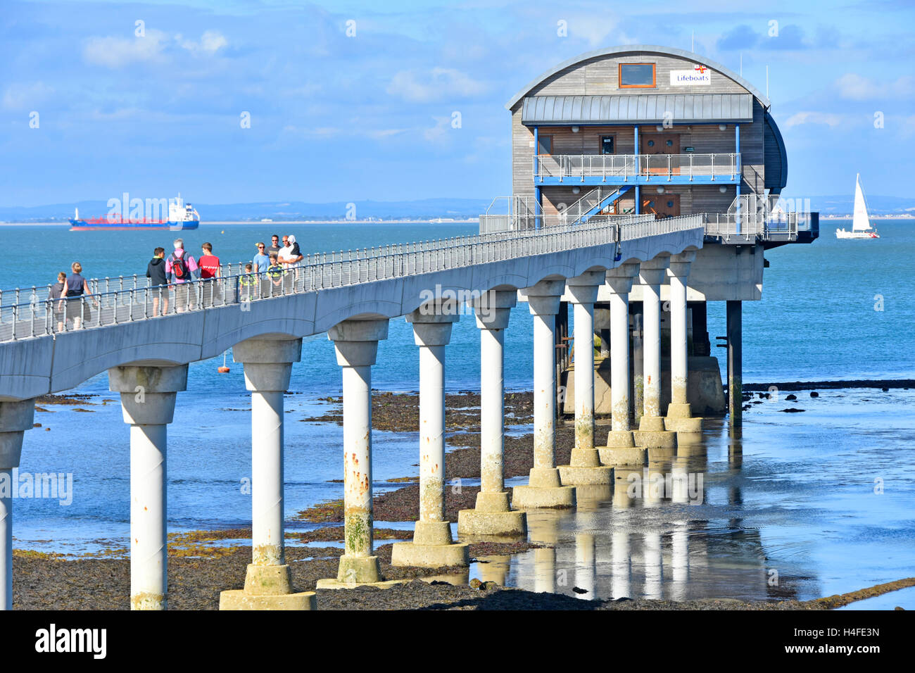 Le persone che visitano Bembridge Isle of Wight RNLI UK scialuppa di salvataggio molo stazione costruita su elevò piattaforma impilati con passerella su pilastri in calcestruzzo Solent oltre Foto Stock
