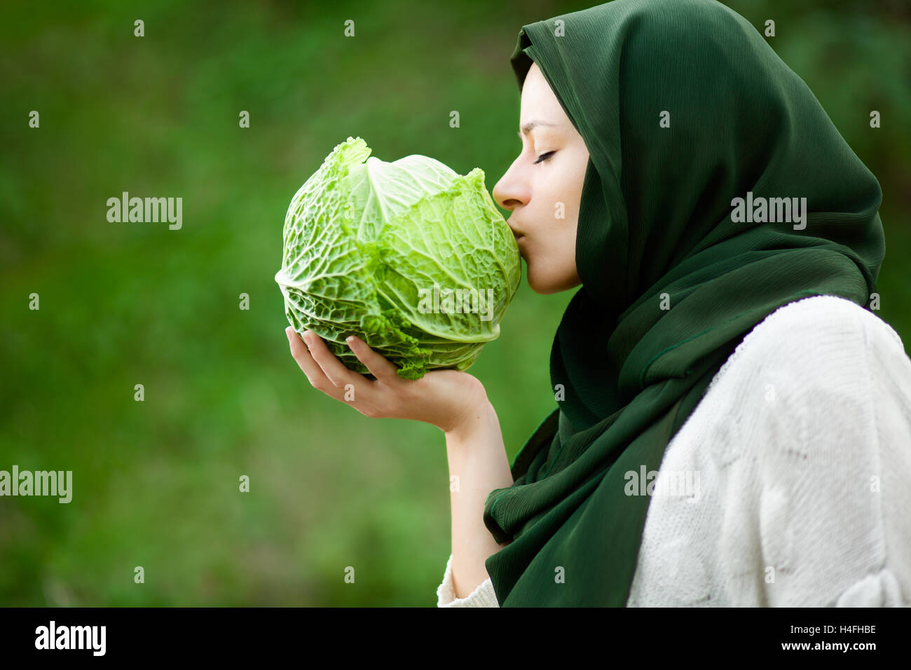 Vegano musulmano donna con velo baciando un cavolo verza Foto Stock