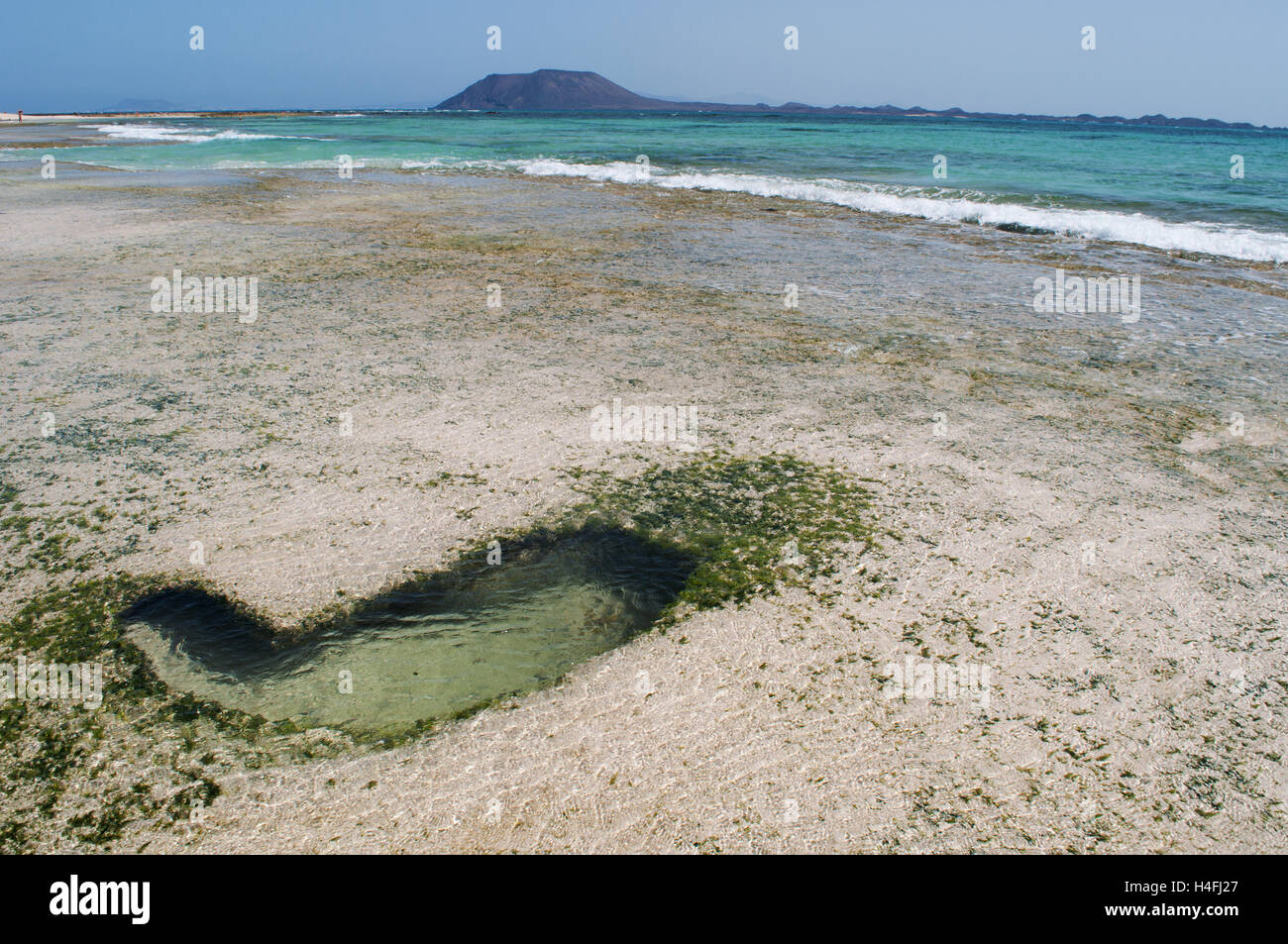 Fuerteventura Isole Canarie, Nord Africa, Spagna: un cuore di roccia a forma durante la bassa marea sulla spiaggia di Grandes Playas con la piccola isola di Lobos Foto Stock