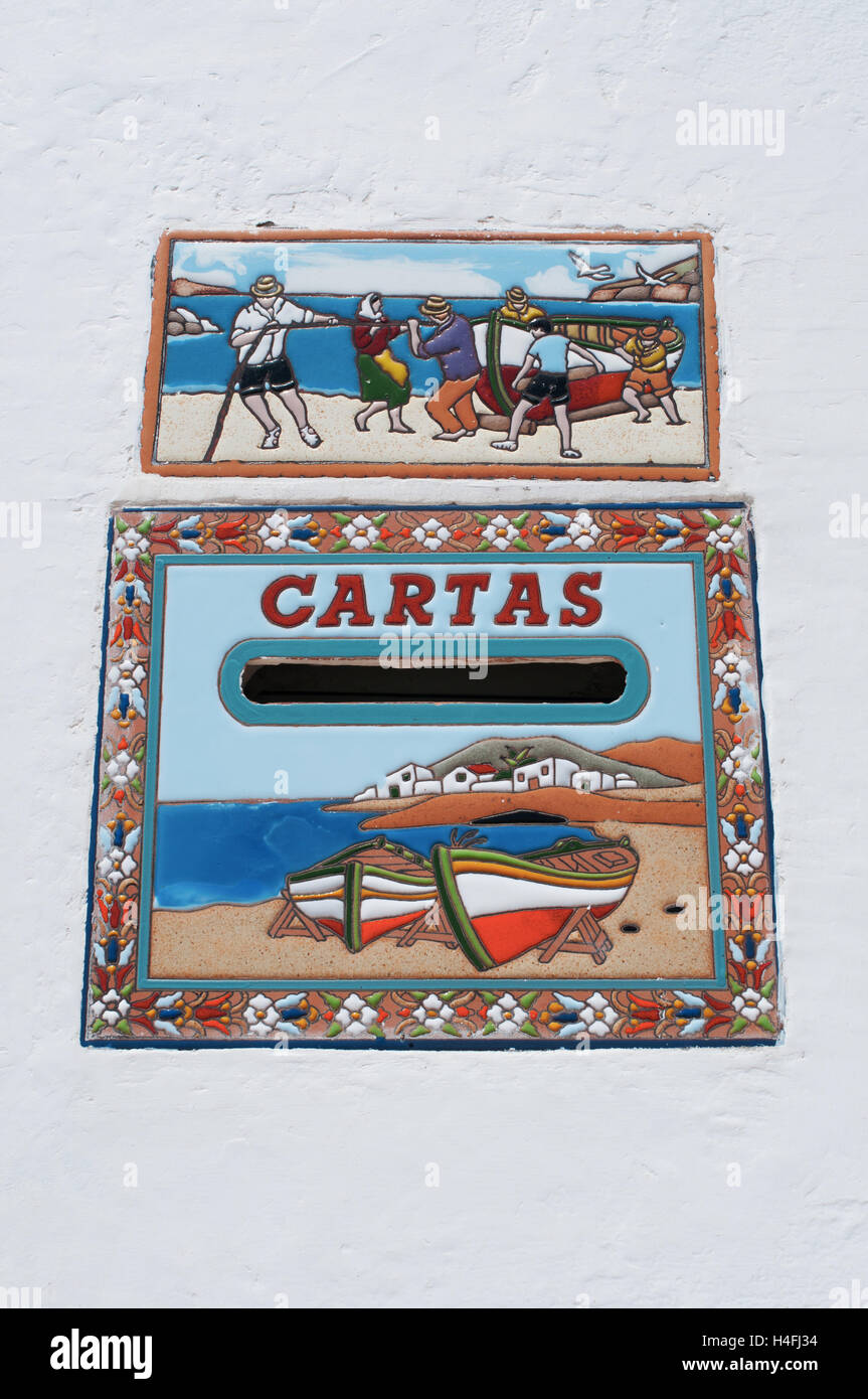 Fuerteventura Isole Canarie, Nord Africa, Spagna: una cassetta postale ed una ceramica tole decorata con scene di pesca e mare su una parete bianca Foto Stock