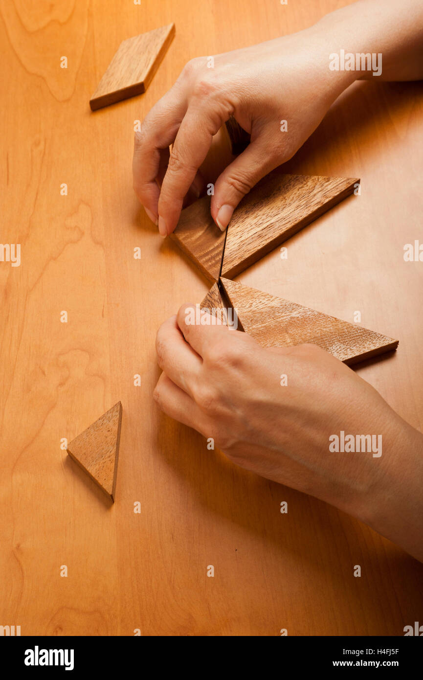 Le mani di una donna che gioca il gioco di Tangram Foto Stock