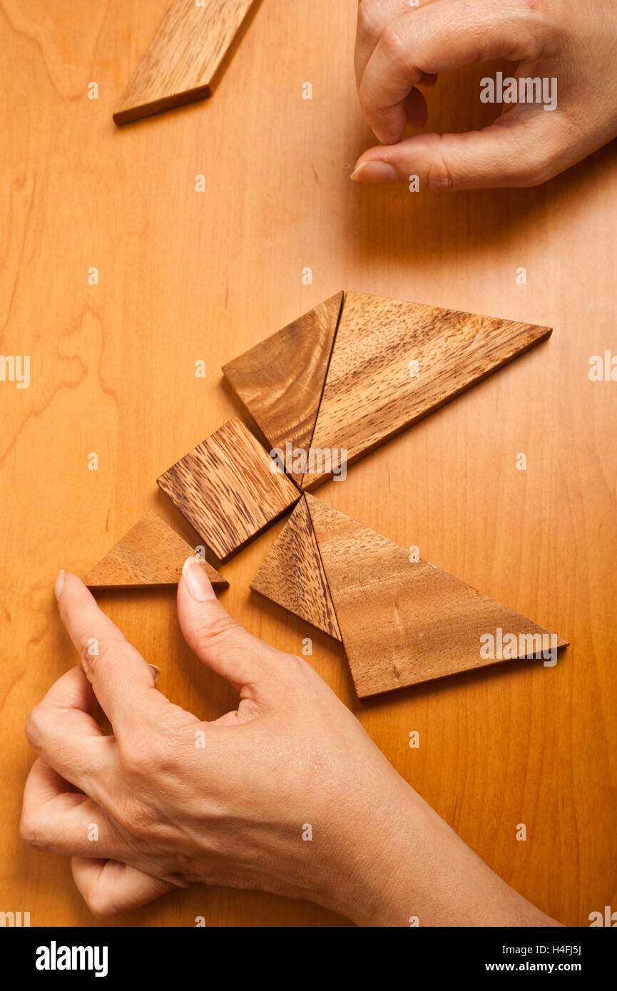 Le mani di una donna che gioca il gioco di Tangram Foto Stock