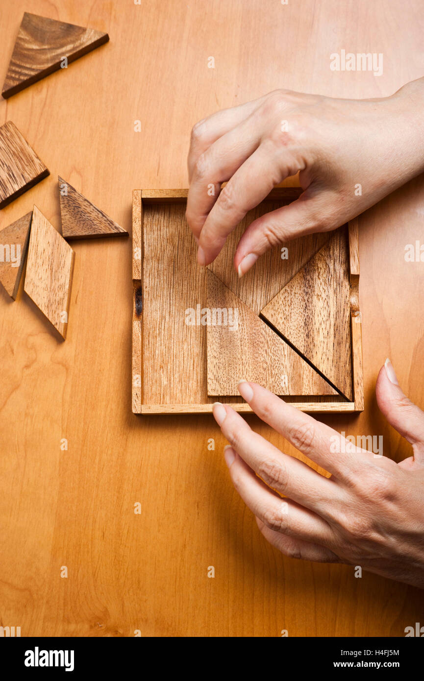 Le mani di una donna che gioca il gioco di Tangram Foto Stock