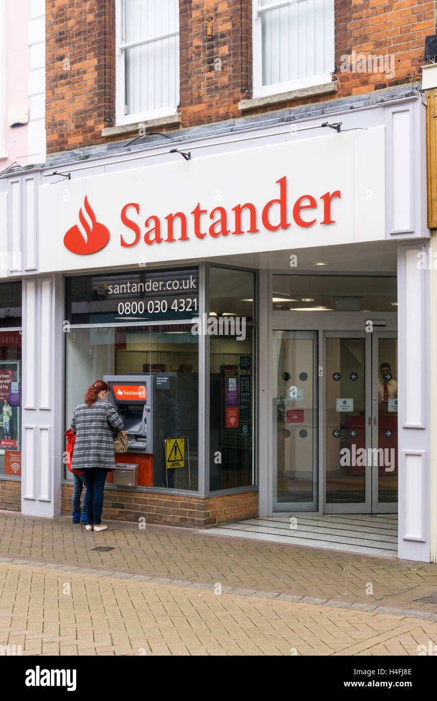 Il cliente utilizza un bancomat al di fuori di una filiale di Santander in King's Lynn, Norfolk. Foto Stock