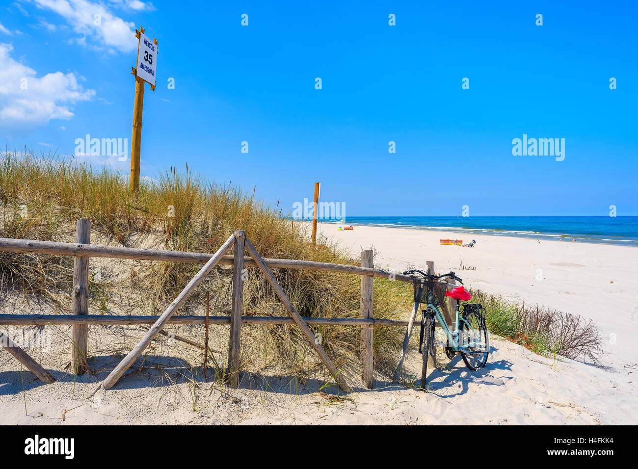Moto parcheggiata all'entrata idilliaca spiaggia sabbiosa in Bialogora villaggio costiero, Mar Baltico, Polonia. Segno sul palo di legno membri 'Ent Foto Stock