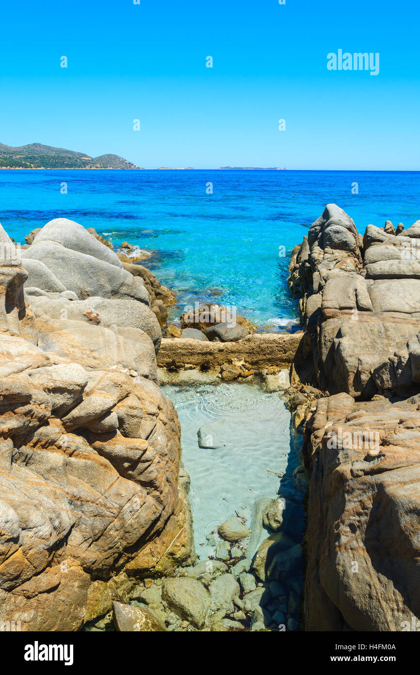 Piscina di acqua di mare in rocce e cristallino mare turchese di Porto Giunco Bay, l'isola di Sardegna, Italia Foto Stock