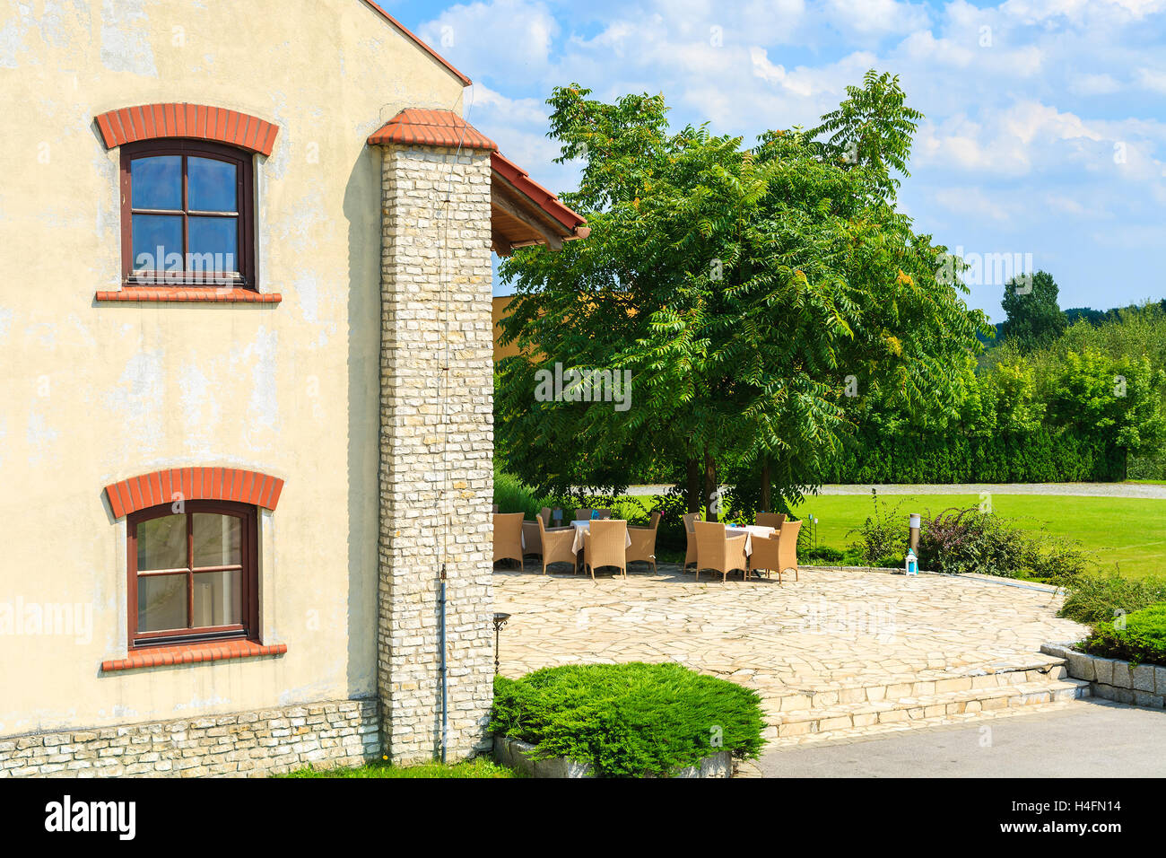 Edificio storico con tavoli e sedie sulla terrazza soleggiata nel villaggio Paczultowice, Polonia Foto Stock