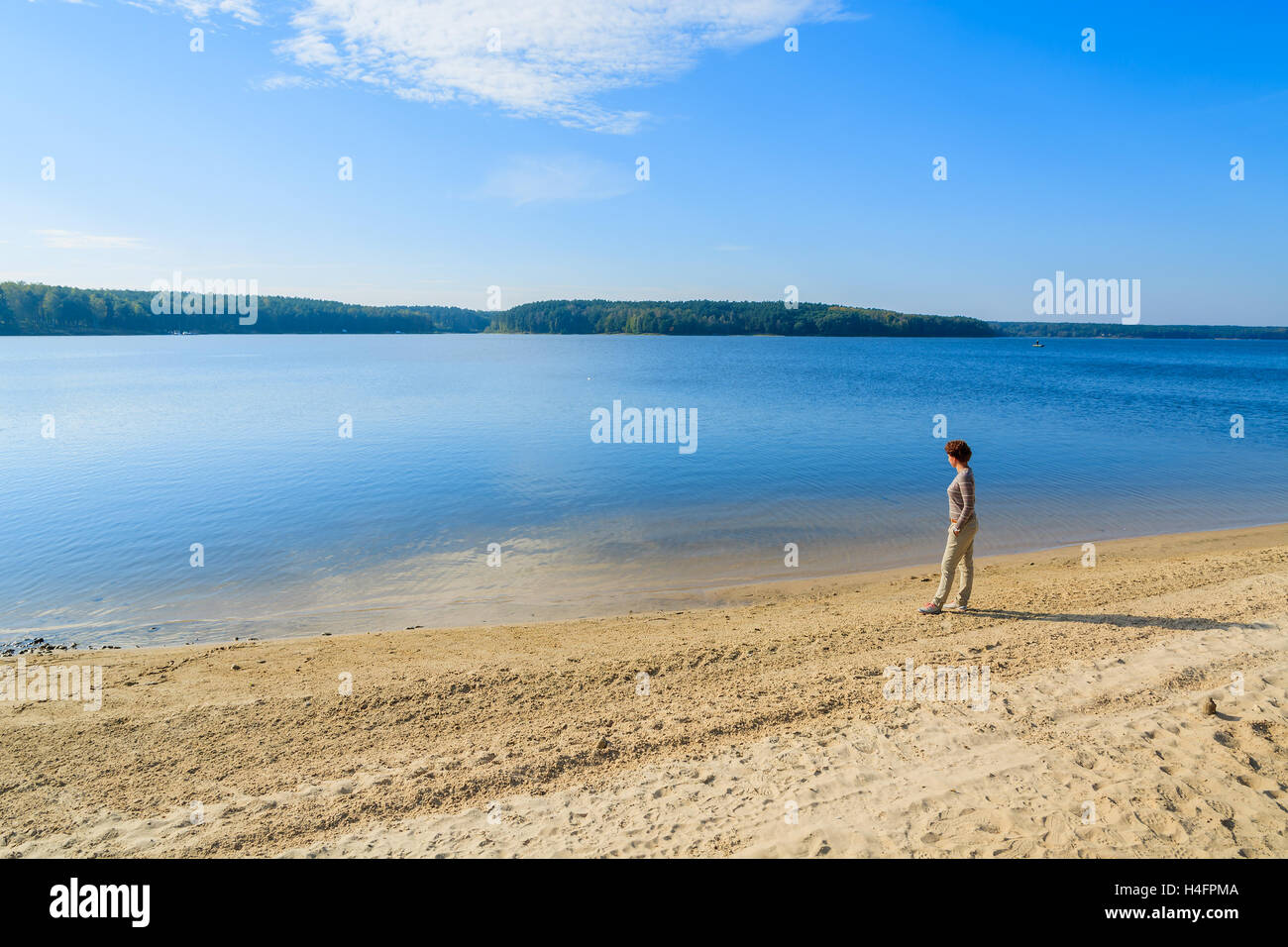 Giovane donna in piedi sulla riva sabbiosa del lago Chancza, Polonia Foto Stock