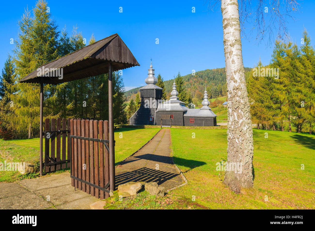 Gate nel parco con la vecchia chiesa di legno in background in Czarna village, Beskid Niski montagne, Polonia Foto Stock