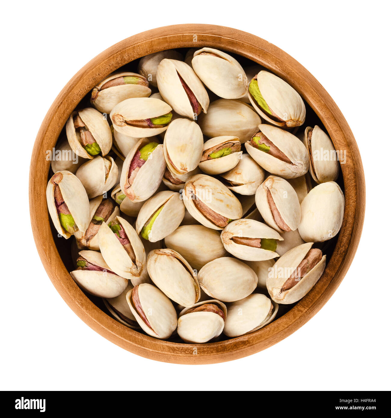 Arrosto di semi di pistacchi con guscio in ciotola di legno su sfondo bianco. Pistacia vera frutti e kernel. Isolato foto macro. Foto Stock