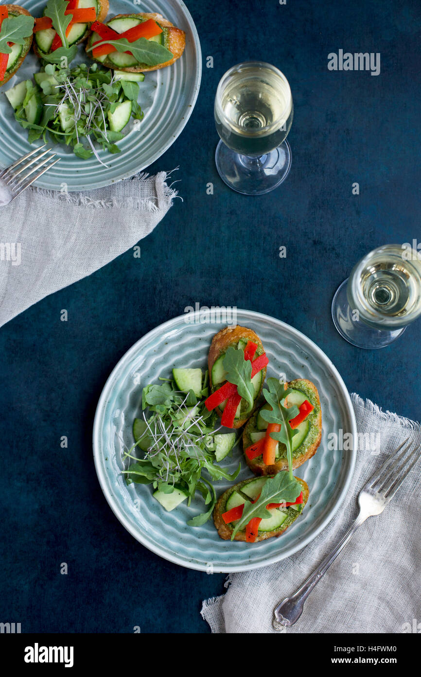 Erba cipollina Crostini di cetriolo, arrosto di peperone rosso e Aruglua fotografato dal di sopra su uno sfondo blu scuro. Foto Stock