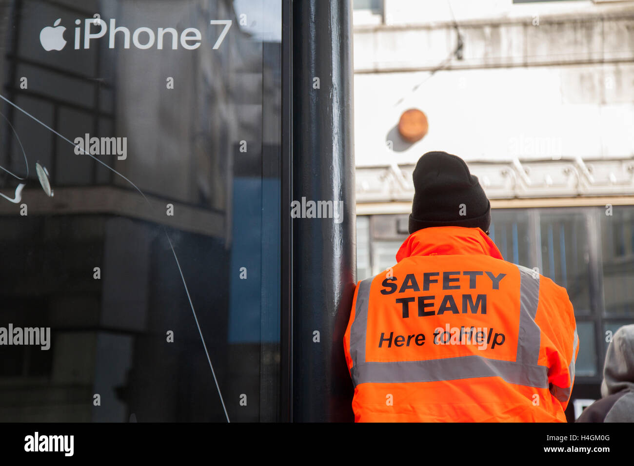 IPhone 7 Pubblicità in Manchester Piccadilly con uomo che indossa ' qui per  aiutare' hi-vis Team Sicurezza camicia, REGNO UNITO Foto stock - Alamy
