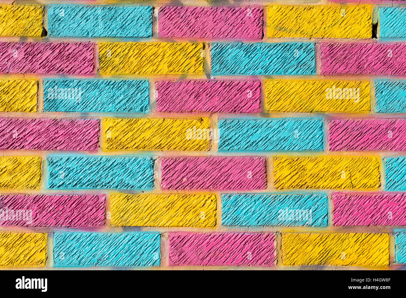 Muro di mattoni dipinto in colore giallo brillante, blu e colori rosa Foto Stock