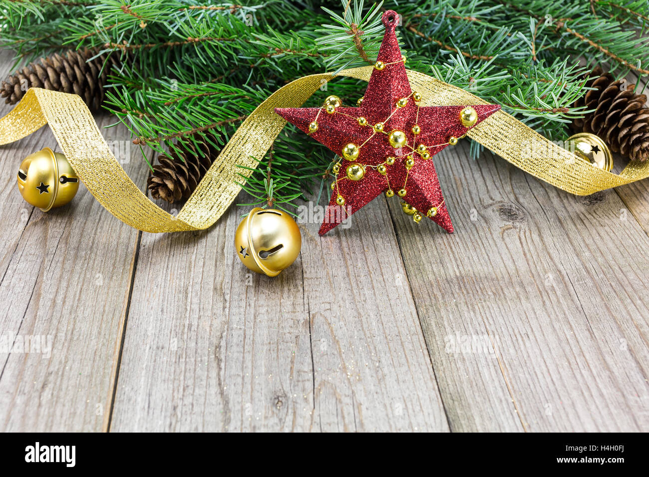 Stella Rossa con ornamento d'oro, Natale Jingle Bells e nastri su weathered tagliere in legno Foto Stock