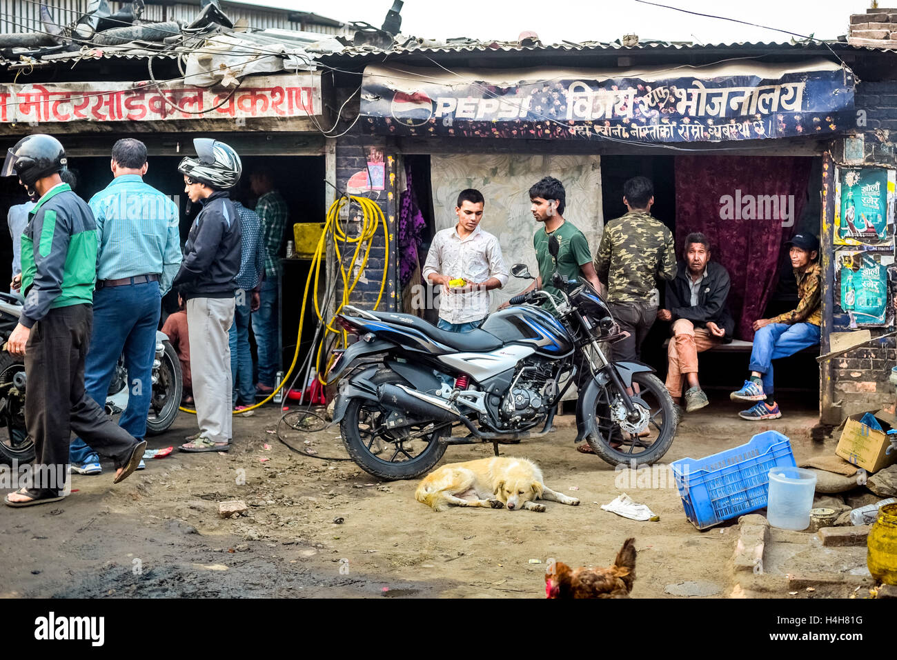Una folla si raduna in un motociclo repair shop di domenica mattina nella periferia di Kathmandu, Nepal. Foto Stock