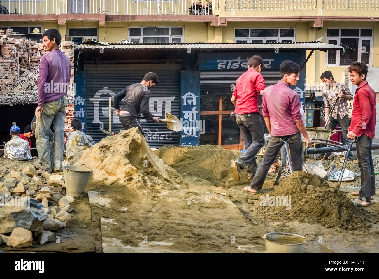 Giovani uomini che lavorano con materiali misti per costruire case nella periferia di Kathmandu, Nepal. Foto Stock