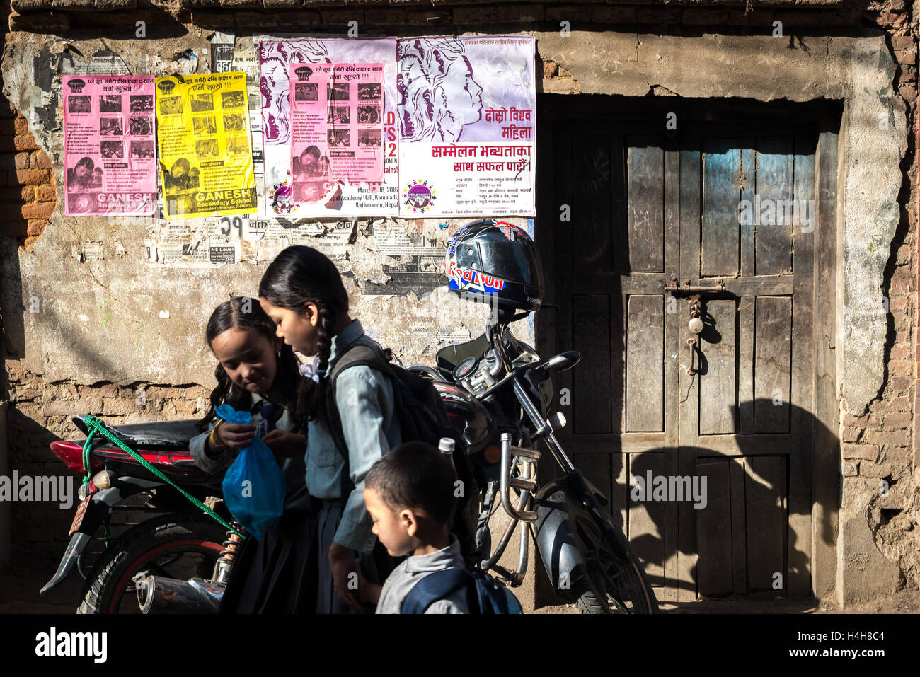 Il nepalese a scuola i bambini a parlare gli uni verso gli altri con commerciale opuscoli sulla parete come sfondo. Foto Stock
