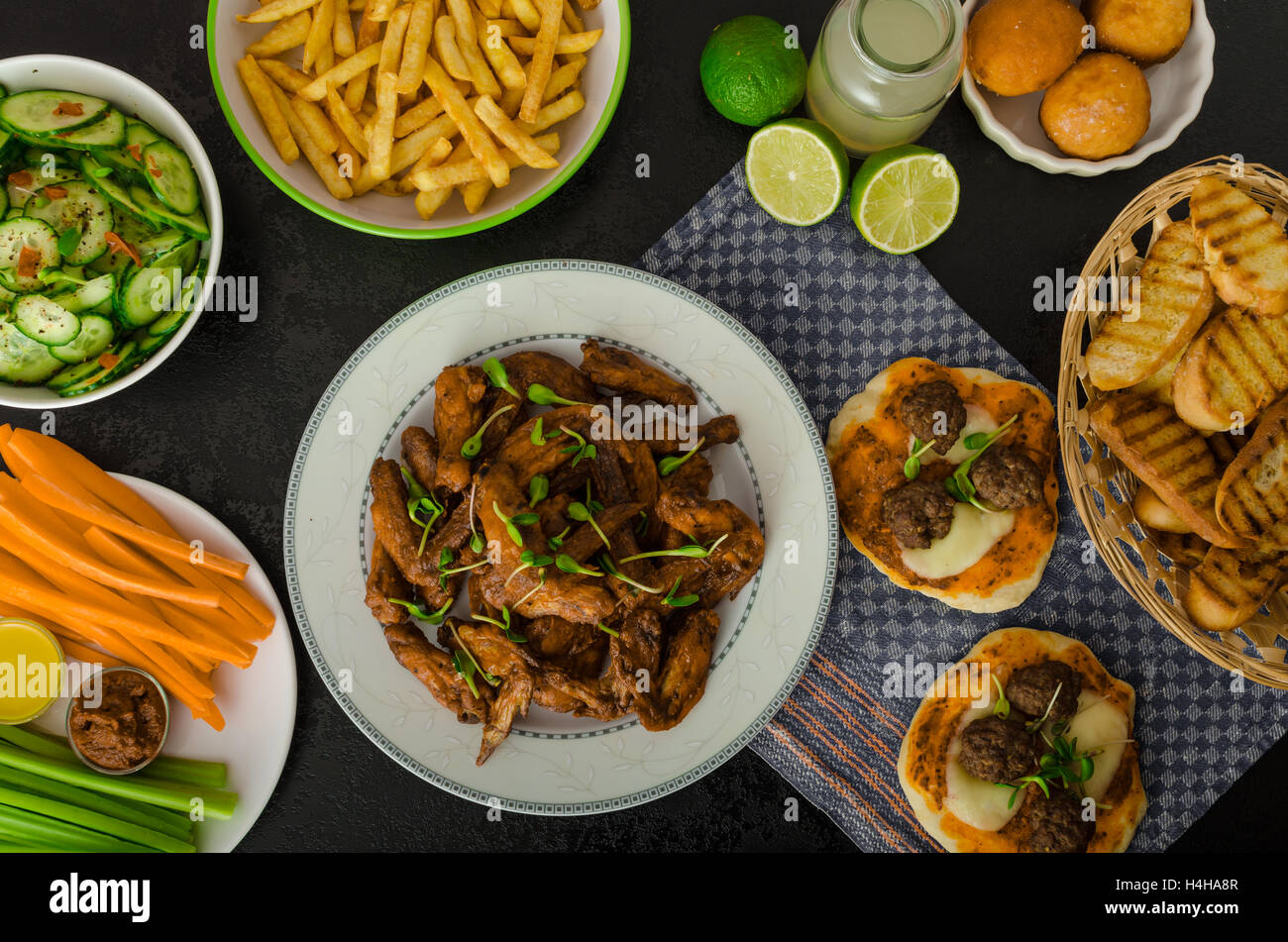 Ali di pollo e verdure, patate fritte, pizza, ciambelle, il succo di lime, dip, insalata di cetrioli e toast. Foto Stock