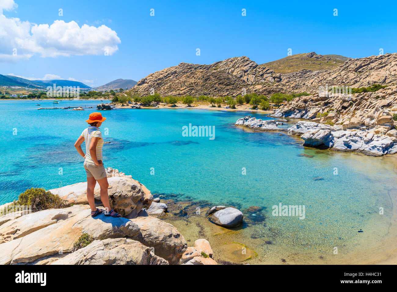 Giovane donna turista in piedi su una roccia e guardando alla bellissima spiaggia di Kolymbithres, isola di Paros, Grecia Foto Stock