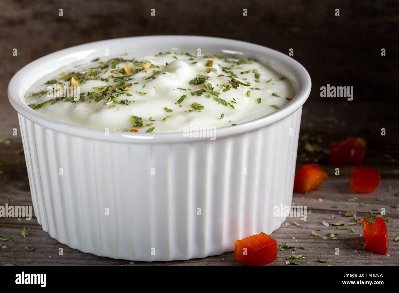 Salsa a base di yogurt e le erbe in un bianco di ceramica ciotola su una tavola di legno Foto Stock