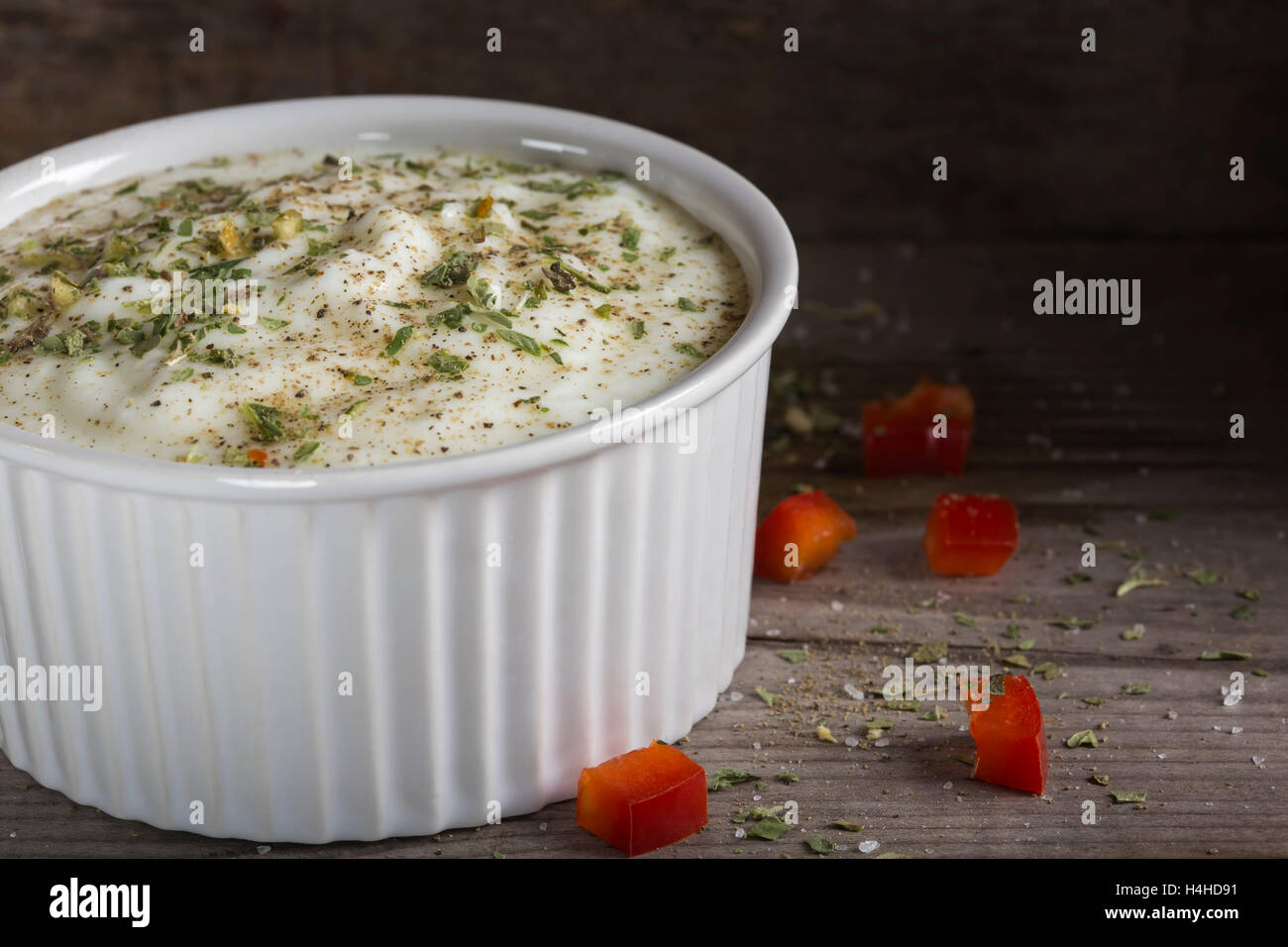 Salsa a base di yogurt e di erbe e di pepe nero in ciotola su una tavola di legno Foto Stock