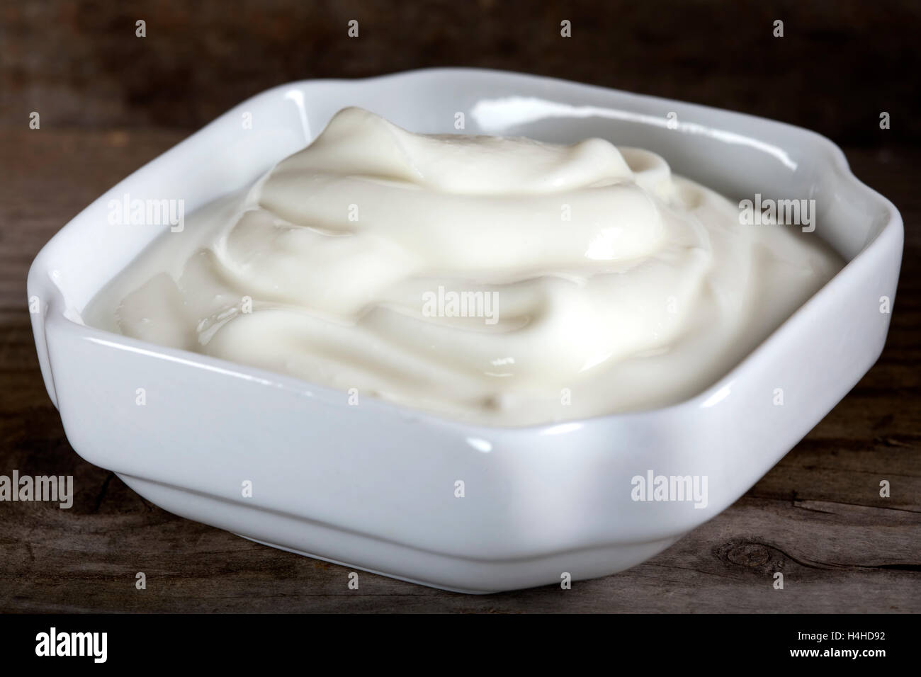 Ciotola di panna acida o yogurt in ciotola bianco su sfondo di legno Foto Stock