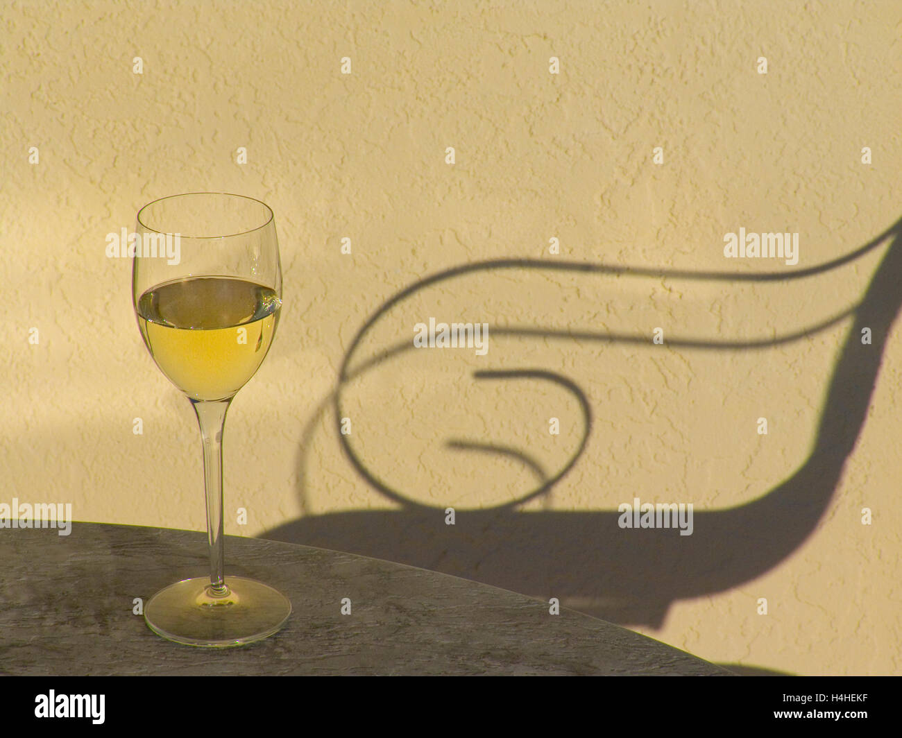VINO BIANCO TRAMONTO VACANZA SEDIA ALL'APERTO RELAX bicchiere di vino bianco sul tavolo soleggiato terrazzo all'aperto con ombra di sdraio all'aperto sedia al tramonto Foto Stock
