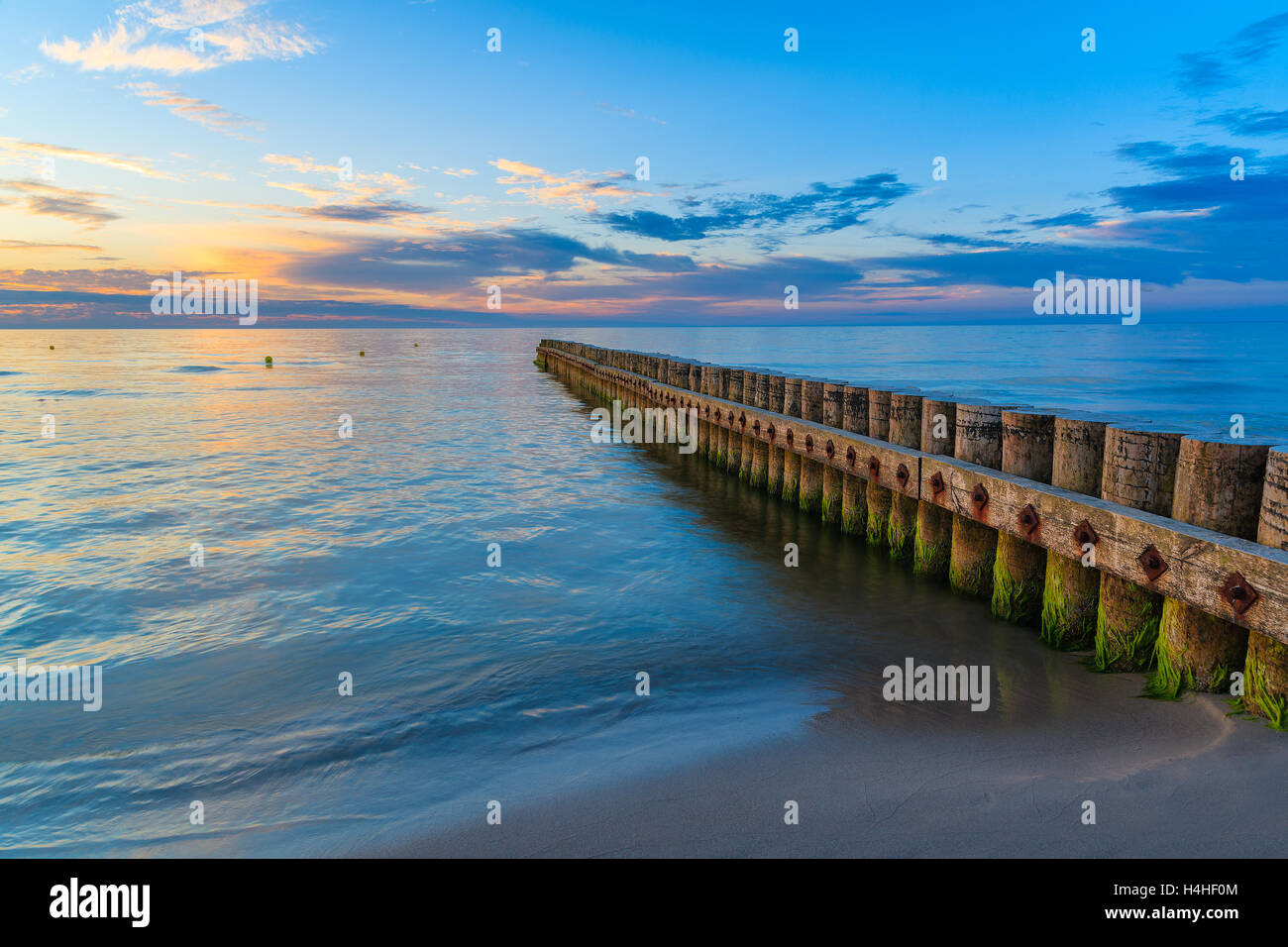 Tramonto sulla spiaggia con un frangiflutti in legno in Leba, Mar Baltico, Polonia Foto Stock