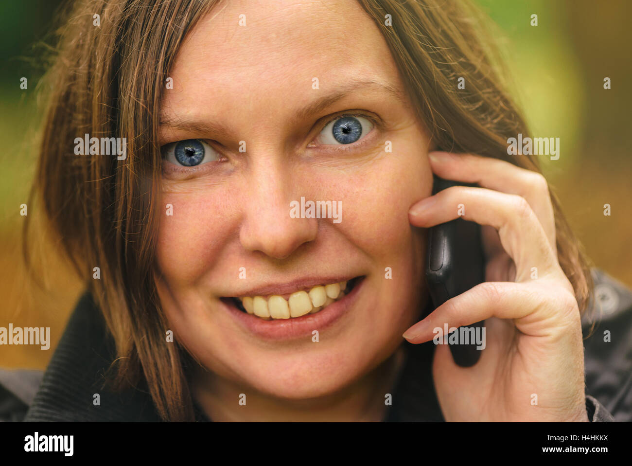 Close up volto ritratto di donna bella parlando al telefono cellulare in autunno park. Giovane femmina adulta persona utilizza lo smartphone per Foto Stock