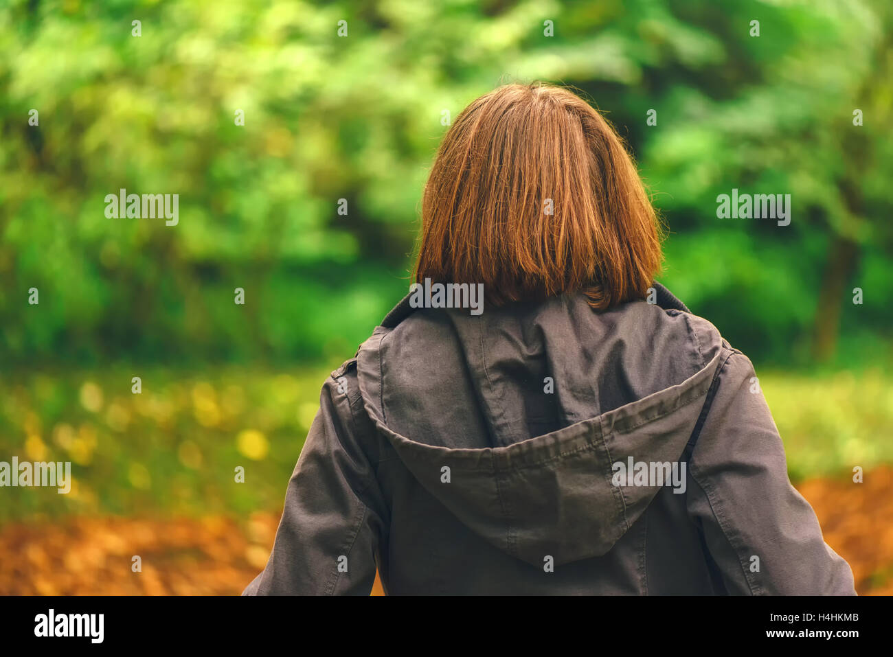 Vista posteriore del casual donna camminando in autunno o parco foresta, donna in caduta stagione ambiente scenario da dietro Foto Stock