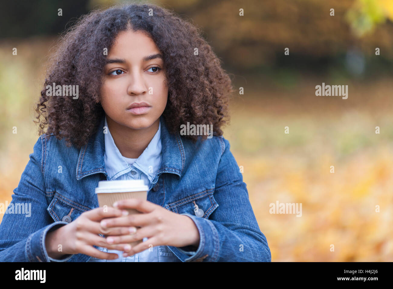 Bella gara di misto americano africano ragazza adolescente femmina giovane donna fuori in autunno autunno guardando triste premuto o riflessivo Foto Stock