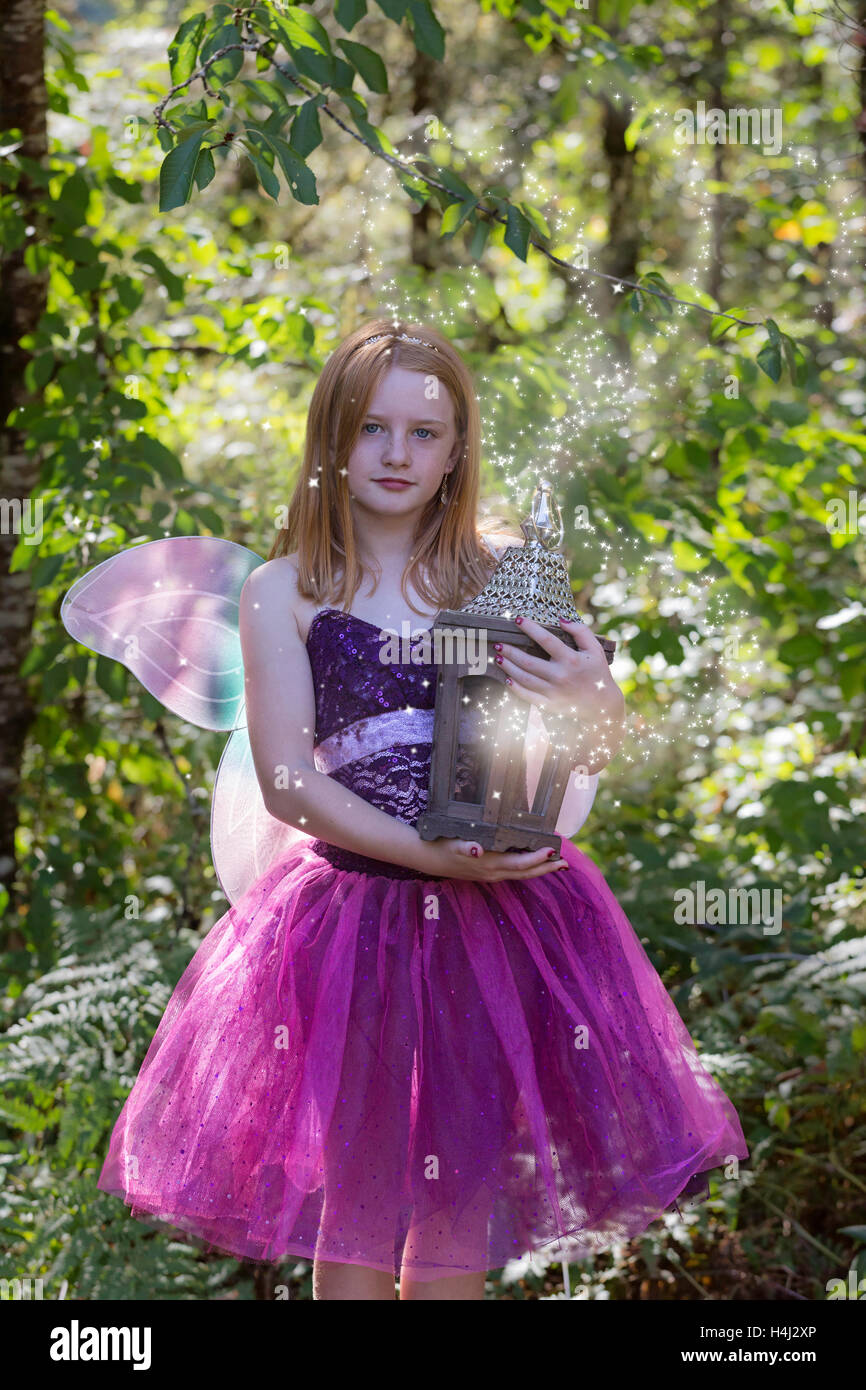 Ragazza giovane vestito in fairy costume di Halloween tenendo un  incandescente fata casa circondata da polvere di fata e bagliori Foto stock  - Alamy