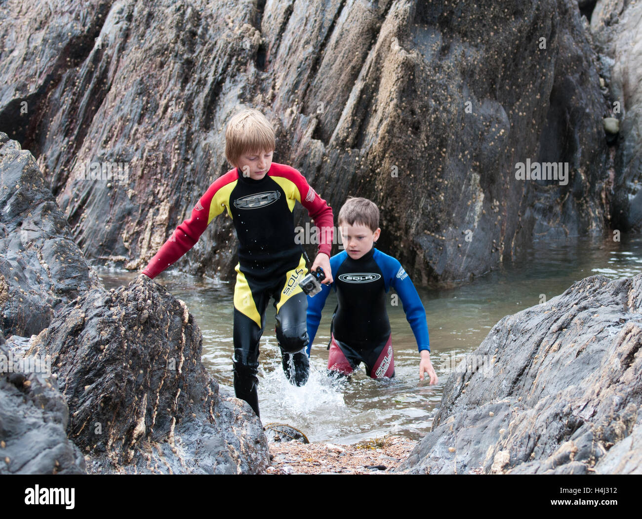 Due ragazzi che emergono dal mare tra rocce Foto Stock