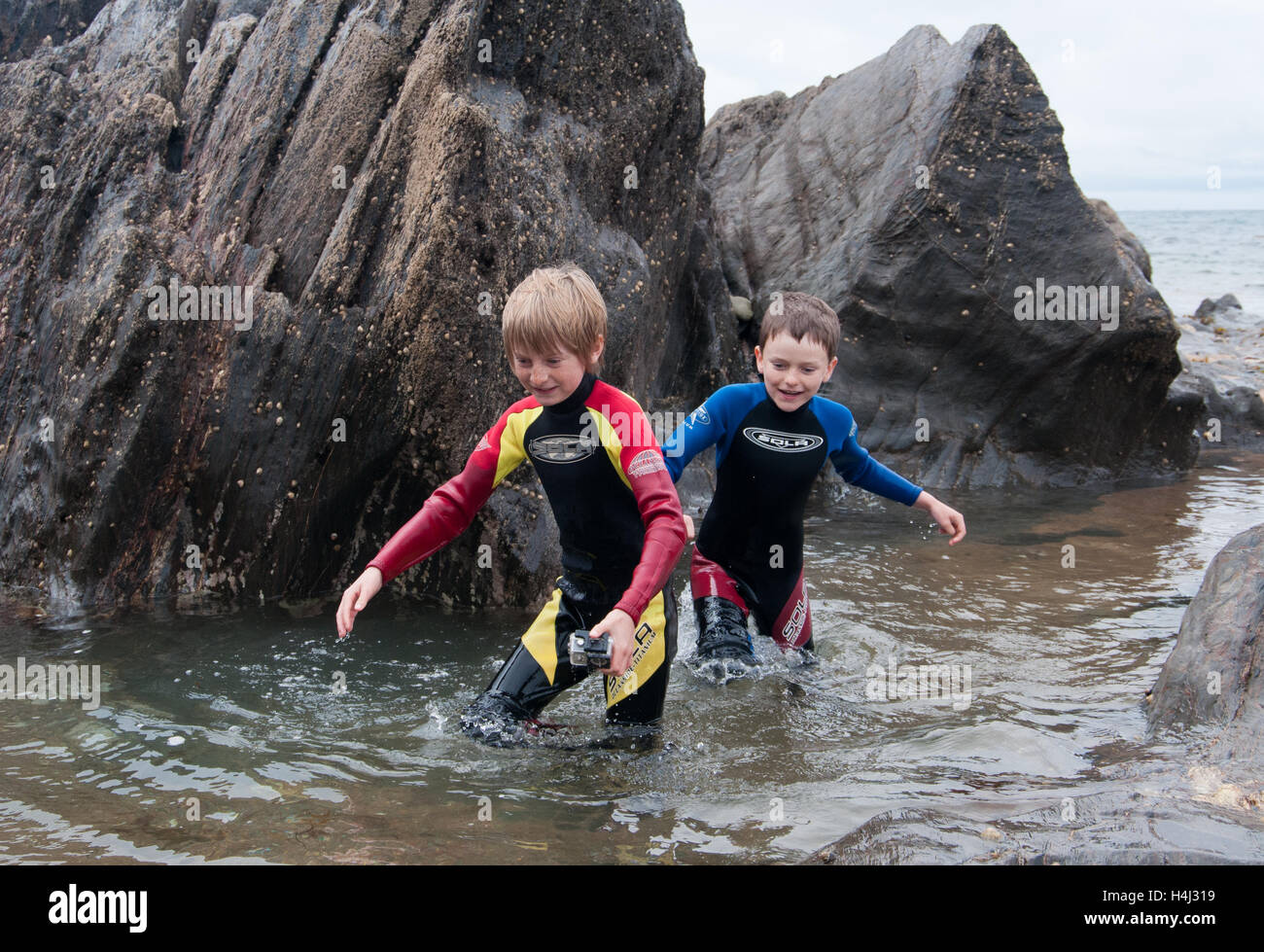 Due ragazzi che emergono dal mare tra rocce Foto Stock