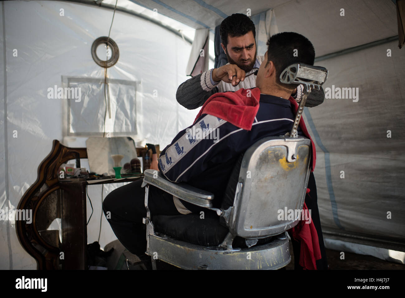 Azaz Refugee Camp vita quotidiana - 03/01/2013 - Siria / Aleppo / Azaz - un barbiere rade un client in una tenda di Azaz Refugee Camp in Siria e Turchia confine. 'Ho diviso il mio prezzo da quattro, ma è un modo per trascorrere il tempo. Uomini venuti e siamo in grado di parlare tutto il giorno" ha detto. Il Azaz Refugee Camp nel nord della Siria, accoglie famiglie cercando di sfuggire le contese tra il siriano esercito governativo e il libero esercito siriano. - Edouard Elias / le Pictorium Foto Stock