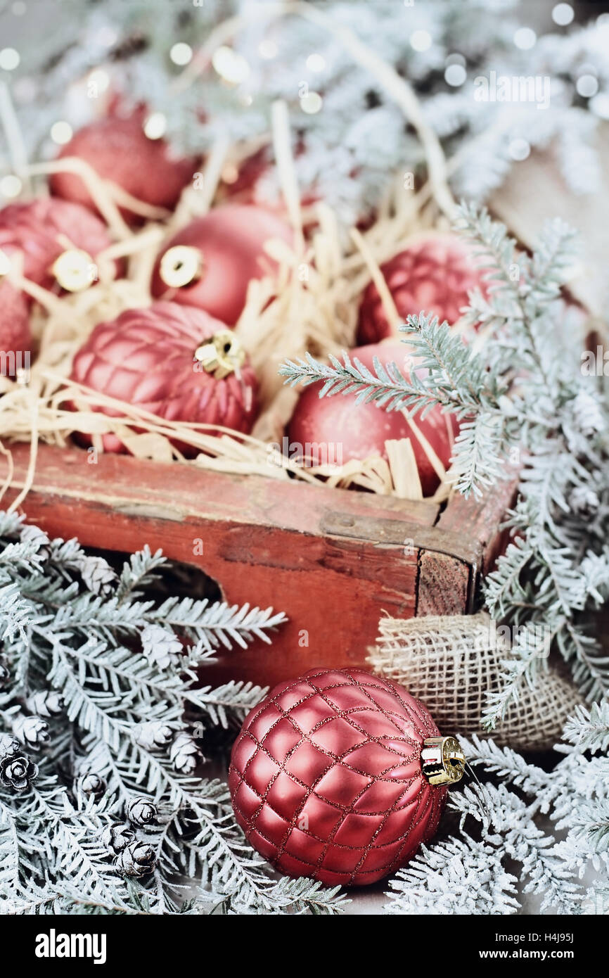 Vetro Ornamenti natale pranzo in un antico scatola di legno con coperte di neve rami di pino che li circondano. Foto Stock
