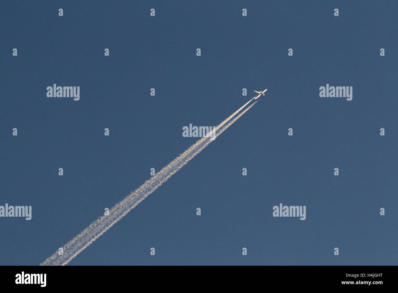 Passeggero aereo jet scie di condensazione con percorsi contro un cielo blu chiaro Foto Stock