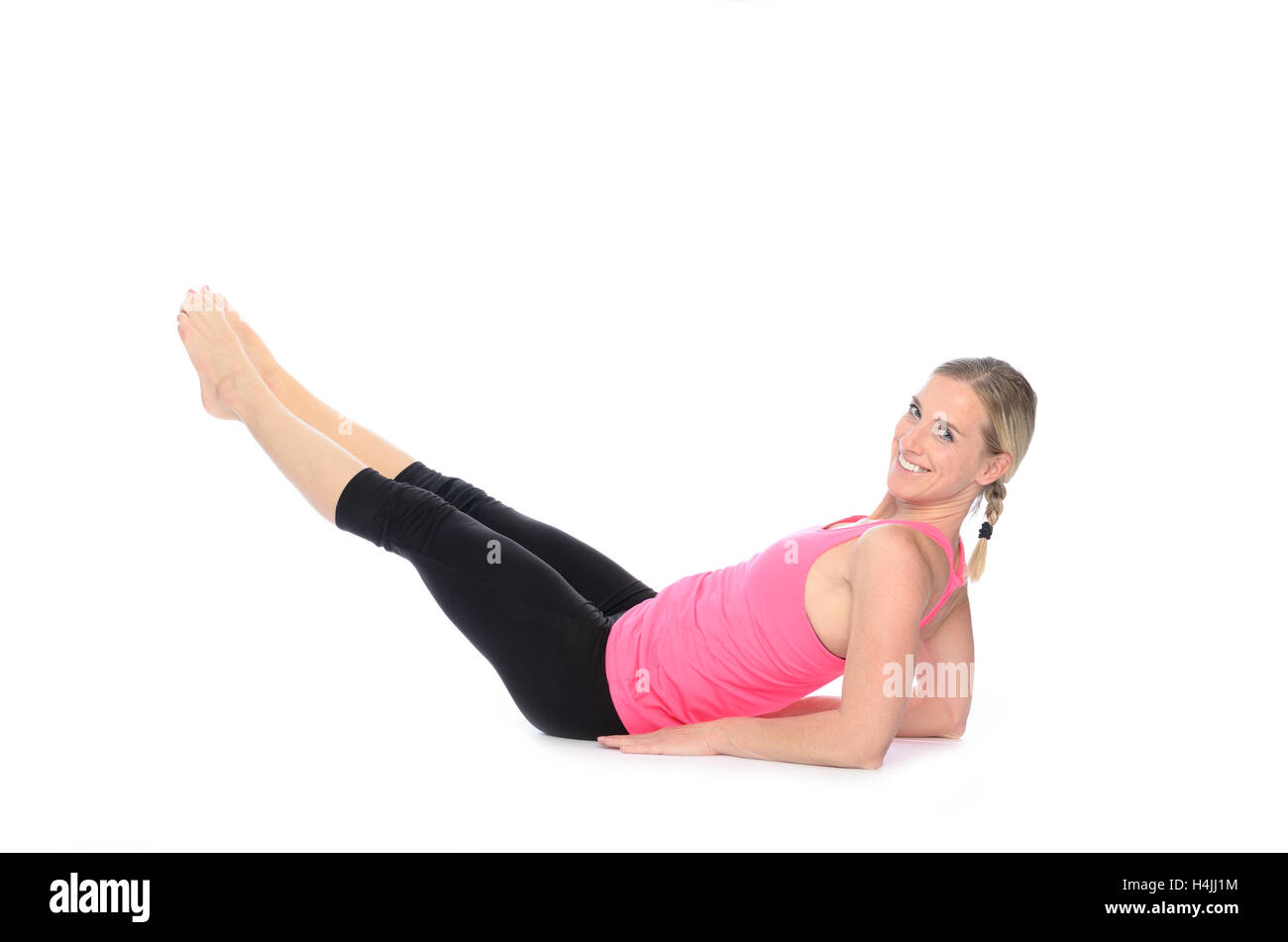 Montare donna sorridente guardando sopra la spalla mentre facendo esercizi addominali con alternanza di estensioni di gamba su sfondo bianco Foto Stock