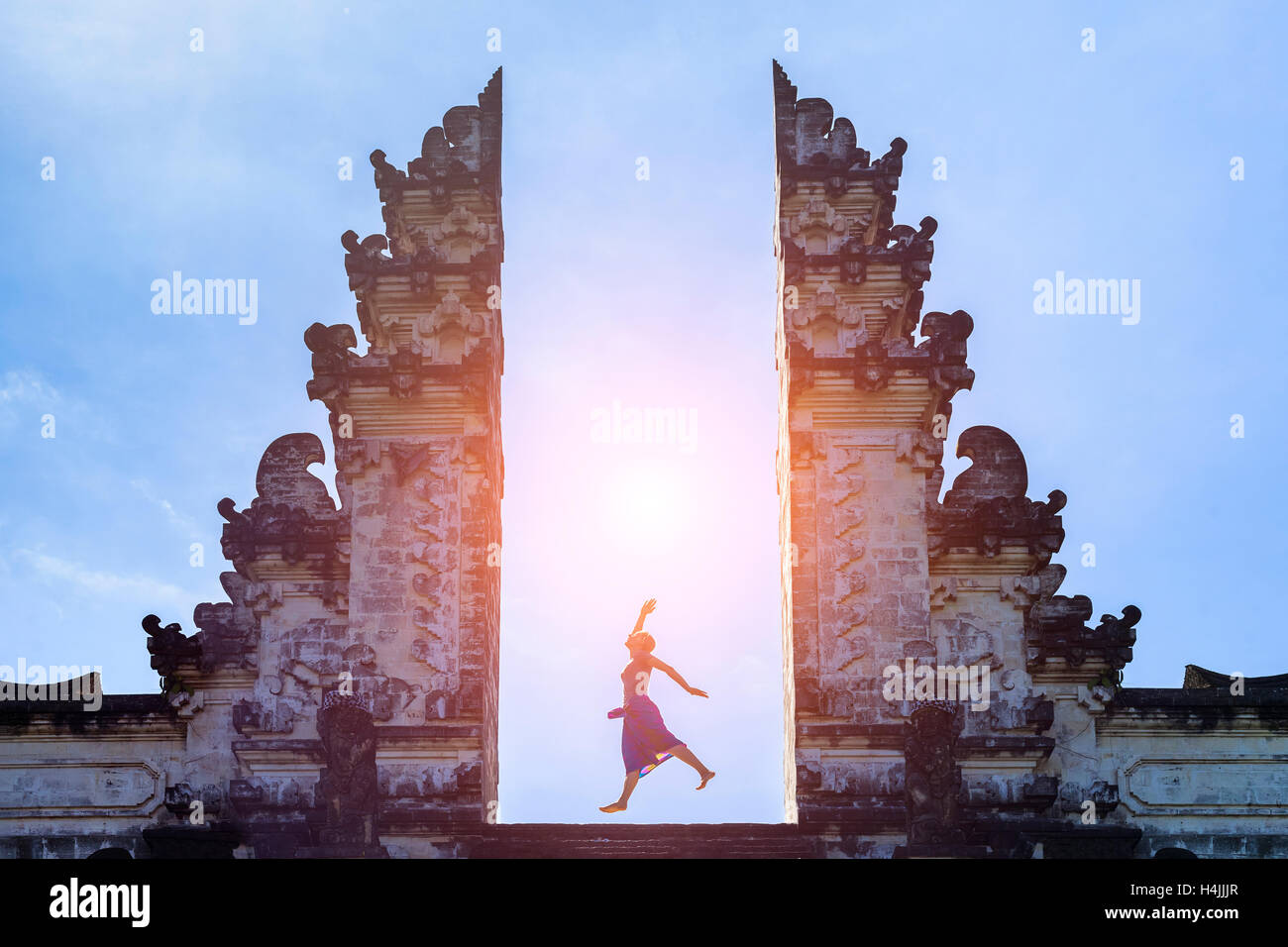 Donna traveler jumping con energia e vitalità alla porta di un tempio, Bali, Indonesia Foto Stock
