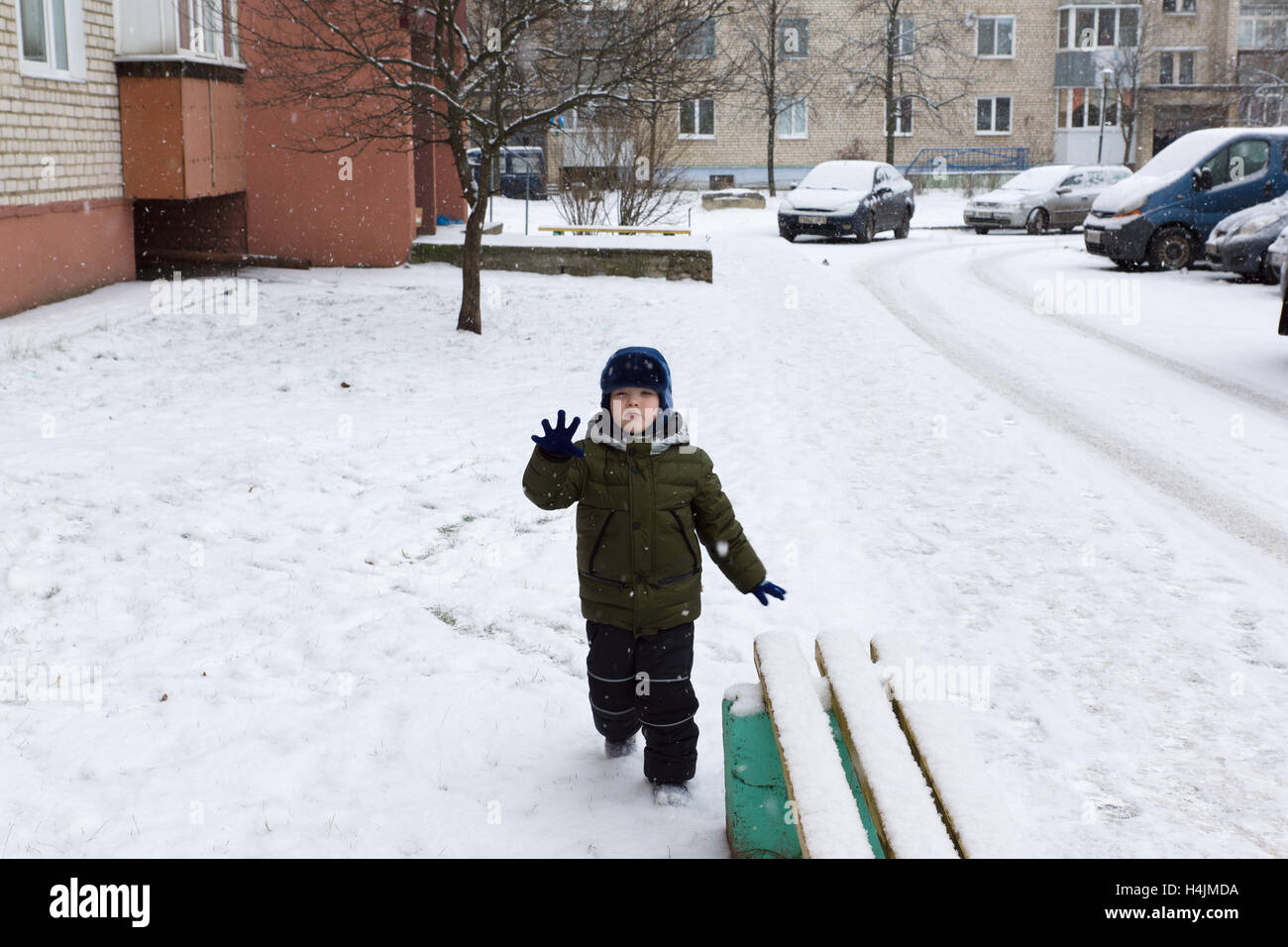 Inverno caldo vestito ragazzo giocando su una strada innevata Foto Stock